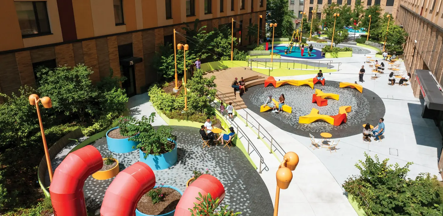 Community members using a brightly colored landscape architect-designed residential courtyard with seating areas, pathways, and planting beds.