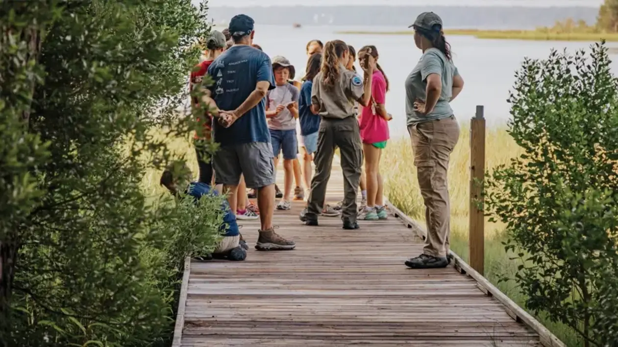 A group of visitors at Machicomoco State Park listening to a park guide